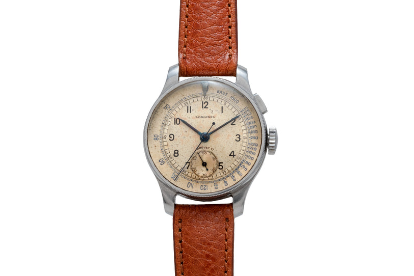Vintage Longines chronograph watch with cream dial, Arabic numerals, and brown leather strap.
