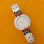 The Cartier Colisee Tutti Frutti Diamond watch features red, green, and blue gemstones on a mustard yellow background.