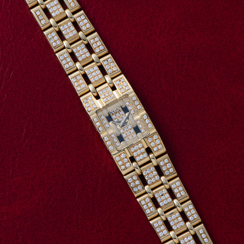 Piaget Polo Pave diamond-encrusted gold wristwatch displayed on a red textured background.