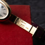 Close-up of a Cartier Baignoire gold watch band engraved with 18K, Swiss Made, and the Cartier logo.