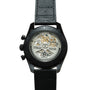 Black chronograph watch with visible skeleton caseback showing gold-tone mechanical movement, black leather strap, and "El Pr