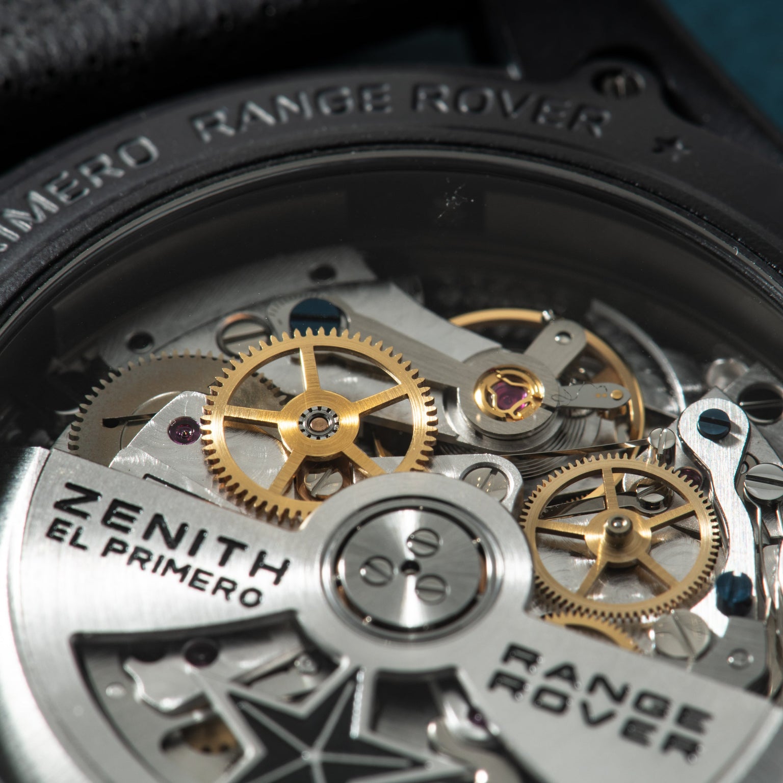 Zenith El Primero chronograph movement with exposed golden gears, jewels, and engraved rotor visible through caseback.