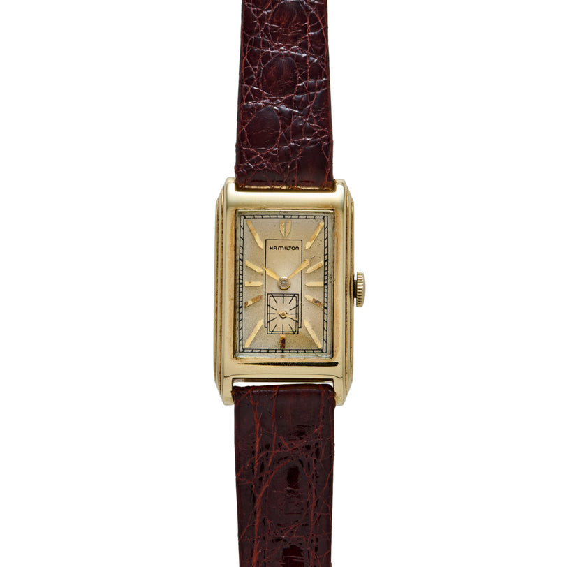 Hamilton Livingstone Art Deco wristwatch with rectangular gold case, cream dial, and burgundy crocodile leather strap.
