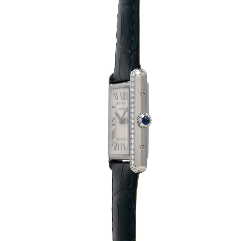 Silver rectangular watch with diamond-set bezel, white dial with Roman numerals, blue sapphire crown, and black leather strap