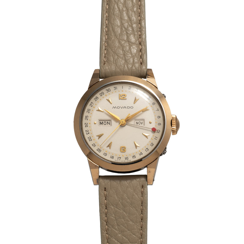 Two-tone Movado watch with cream dial, day-date window, and tan leather strap.