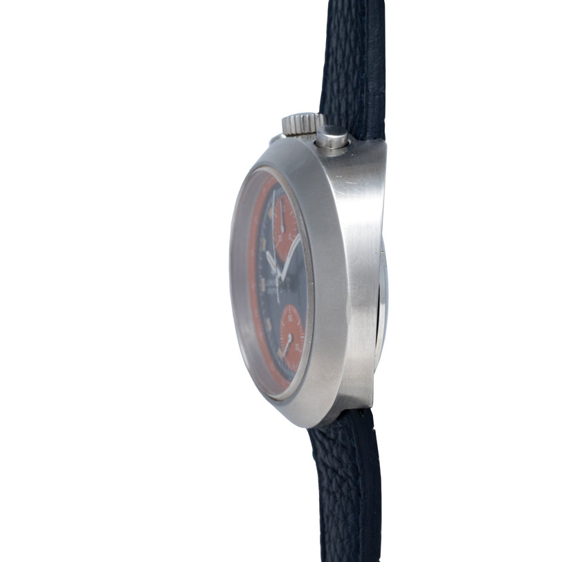 Stainless steel chronograph watch with dark blue dial and red accents, displayed on black textile strap.