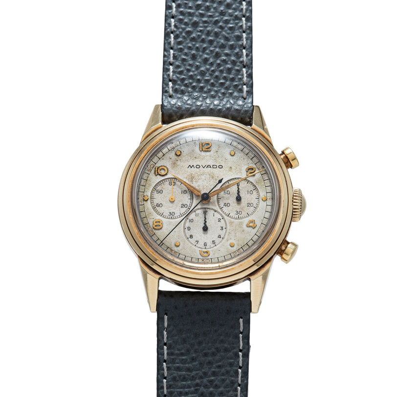 Movado M95 chronograph with gold-tone case, cream dial, three subdials, and dark leather strap.