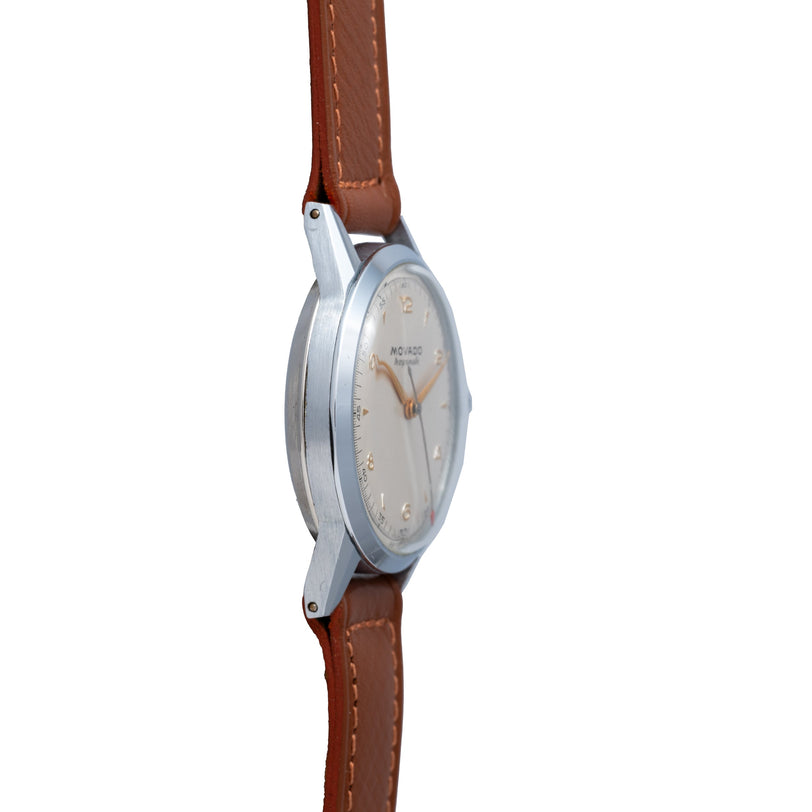 Movado Tempomatic watch with brushed steel case, cream dial, and brown leather strap with contrast stitching.