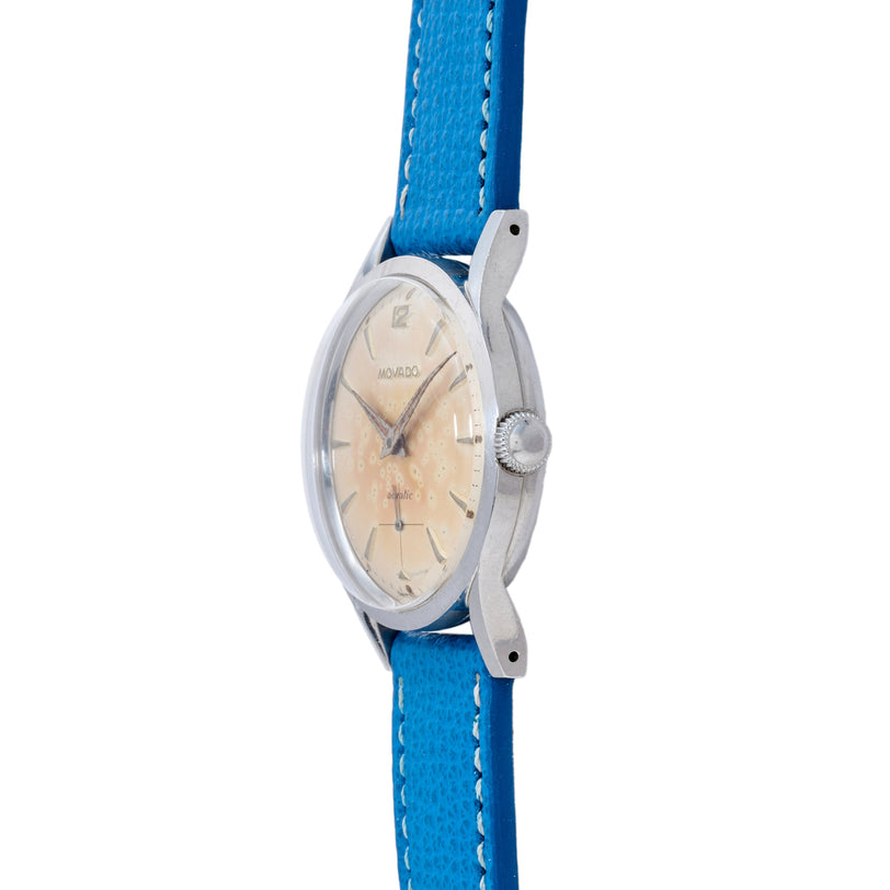 Movado Acvatic dress watch with cream dial, silver case, and blue leather strap with white stitching.