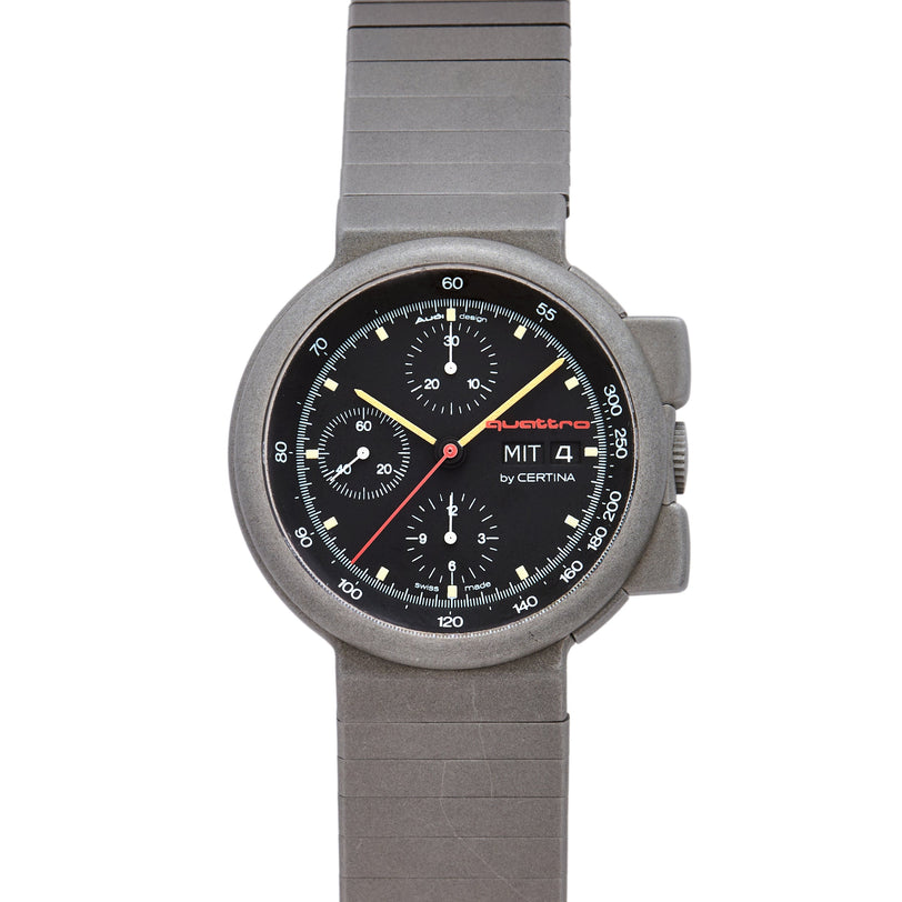 Titanium chronograph watch with black dial, three subdials, yellow and red hands, Audi Sport branding, and metal bracelet.
