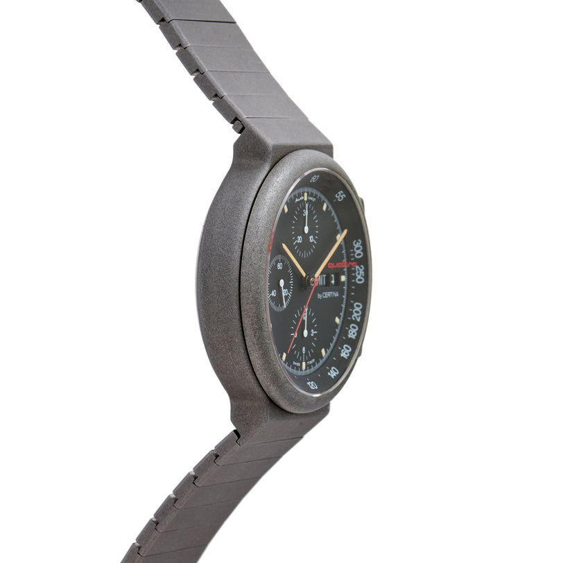 Certina chronograph watch with dark dial, multiple subdials, red accents, and gray metal bracelet shown from side angle.