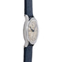 A side view of the Movado 'Calatrava' Steel shows its silver case, cream dial, and navy blue textured strap with dark hour markers and hands, displayed against a white background.