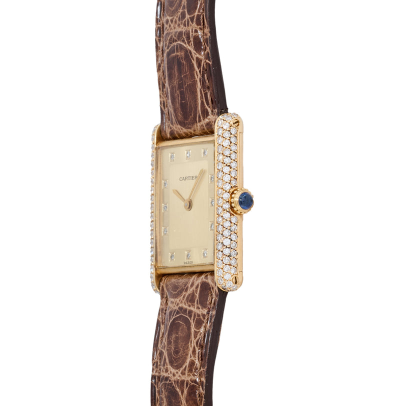 Gold rectangular Tank watch with diamond-set bezel, cream dial, blue sapphire crown, and brown crocodile leather strap.