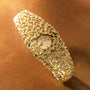 Gold-toned bracelet watch with textured organic surface design and round dial embedded in center.