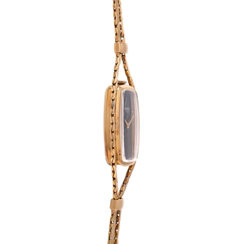 Gold-tone chain necklace with rectangular watch pendant featuring dark dial and geometric hands.