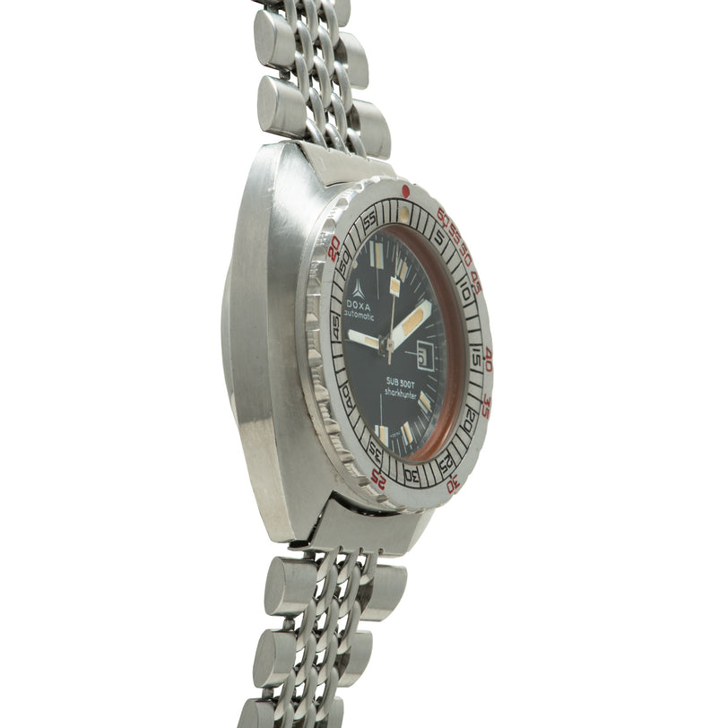 Stainless steel dive watch with black dial, red bezel markings, applied hour markers, and matching metal bracelet.