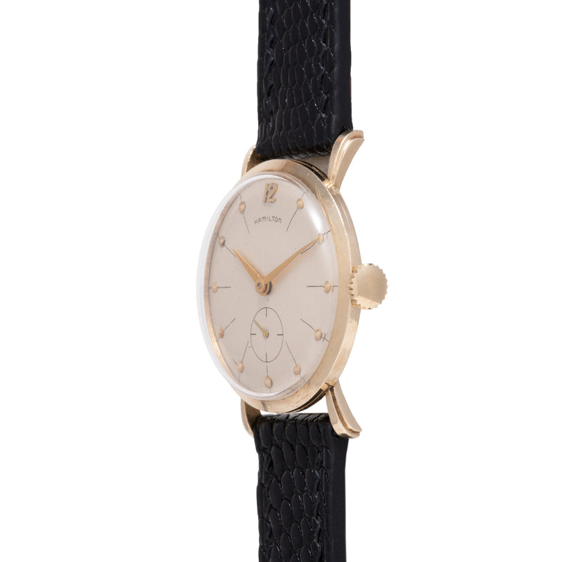 Hamilton Bradford oval watch with cream dial, Arabic numerals, gold-tone hands, subdial, and black leather strap.
