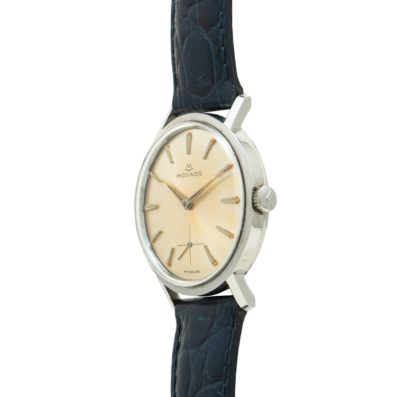 Movado Sub Sea watch with stainless steel oval case, cream dial, gold-tone indices, and dark blue leather strap.