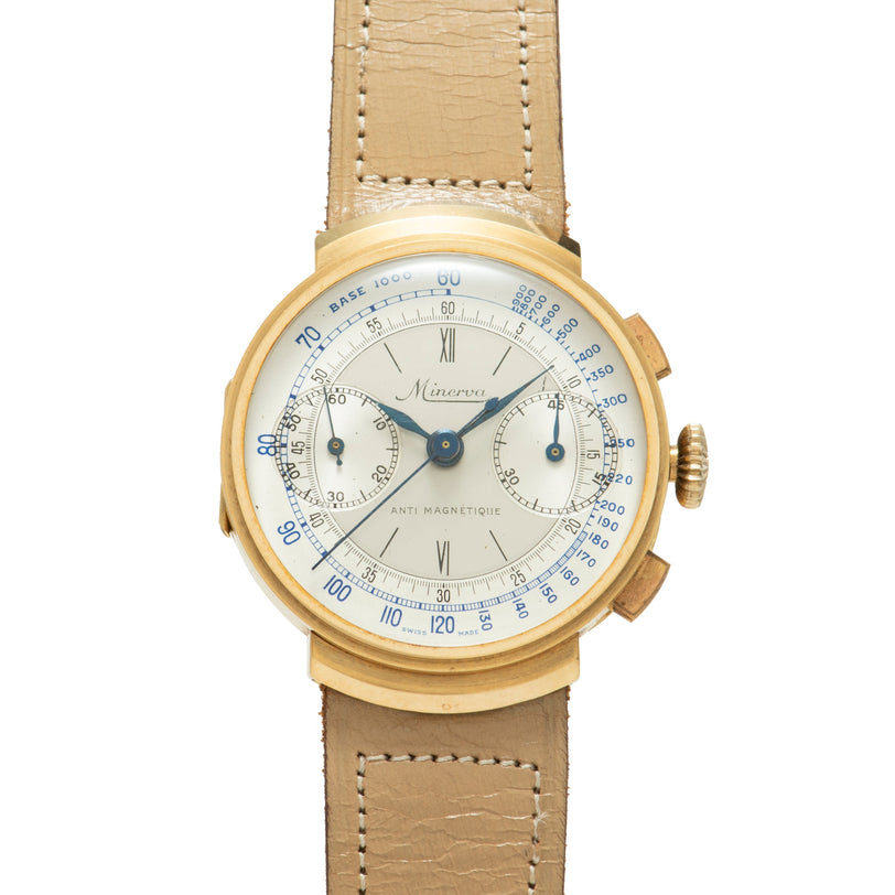 Gold-tone Minerva chronograph watch with cream dial, Roman numerals, blue tachymeter scale, and tan leather strap.