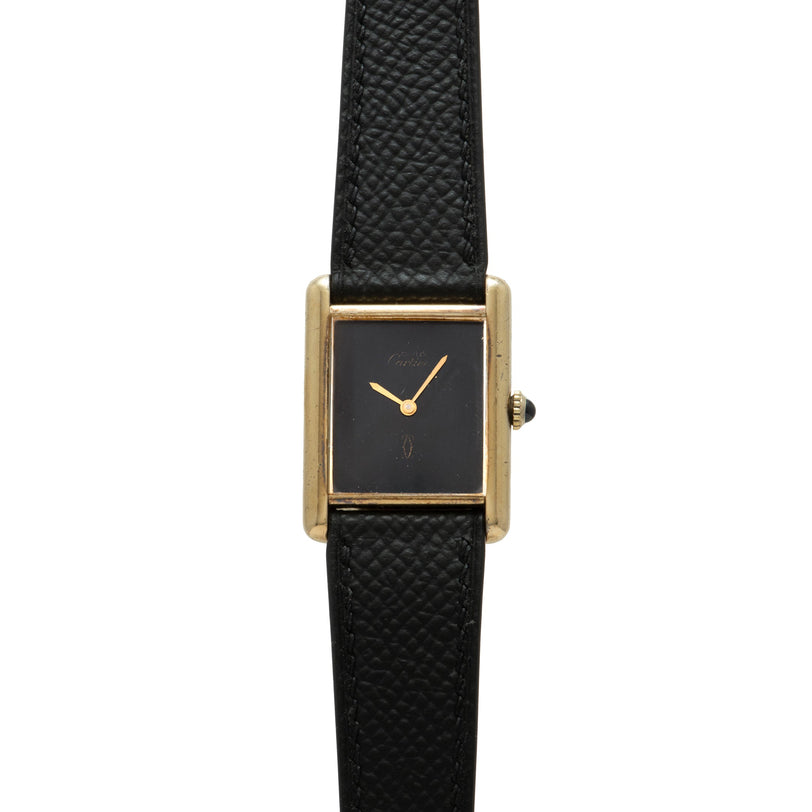 Gold-tone rectangular watch with black dial, gold hands, and black quilted leather strap.