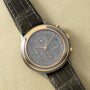 Two-tone chronograph watch with charcoal dial, three subdials, and black leather crocodile-embossed strap.