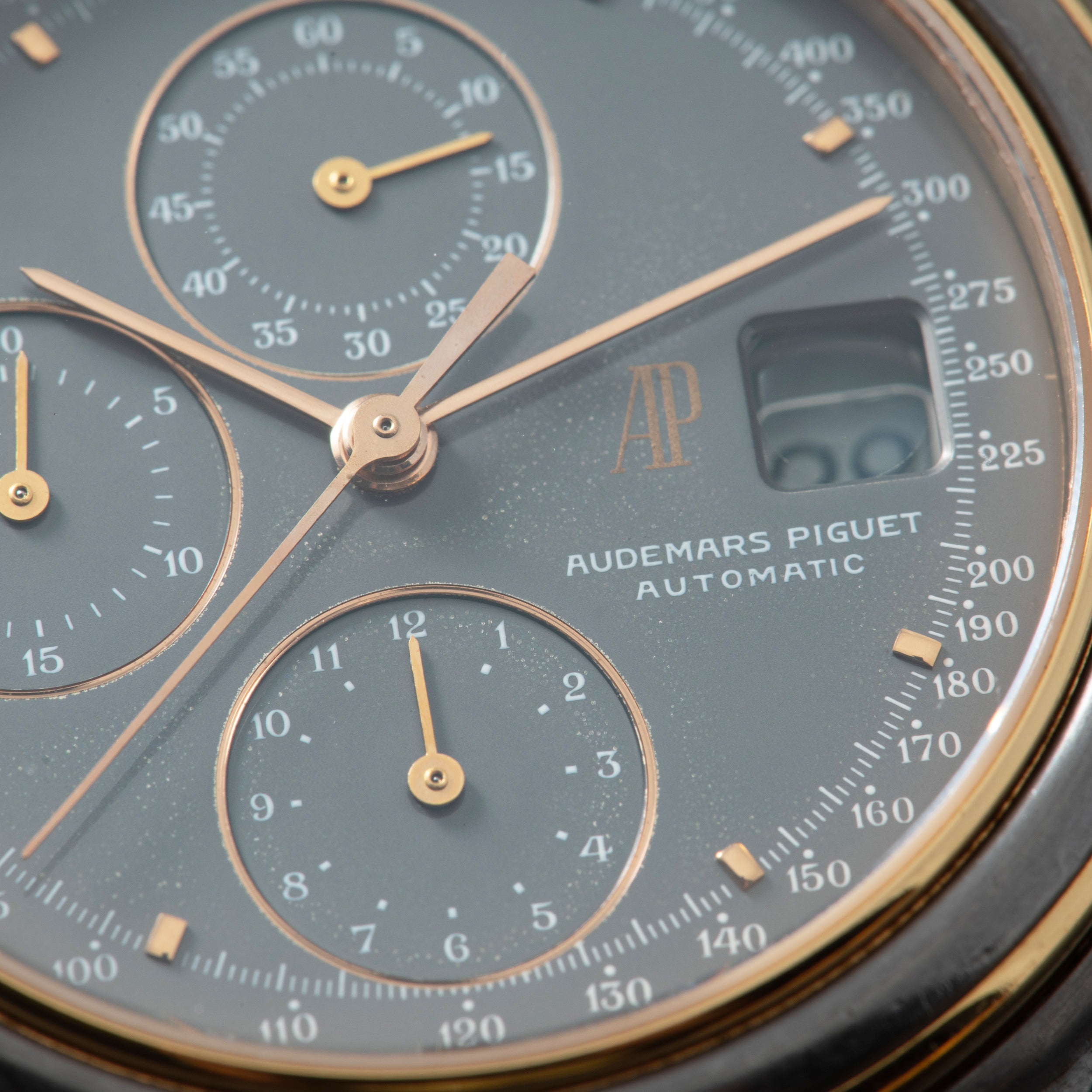 Audemars Piguet chronograph watch dial with gray face, multiple subdials, rose gold hands, and tachymeter scale.