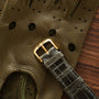 Gray crocodile leather watch strap with gold-tone buckle on olive perforated leather glove.