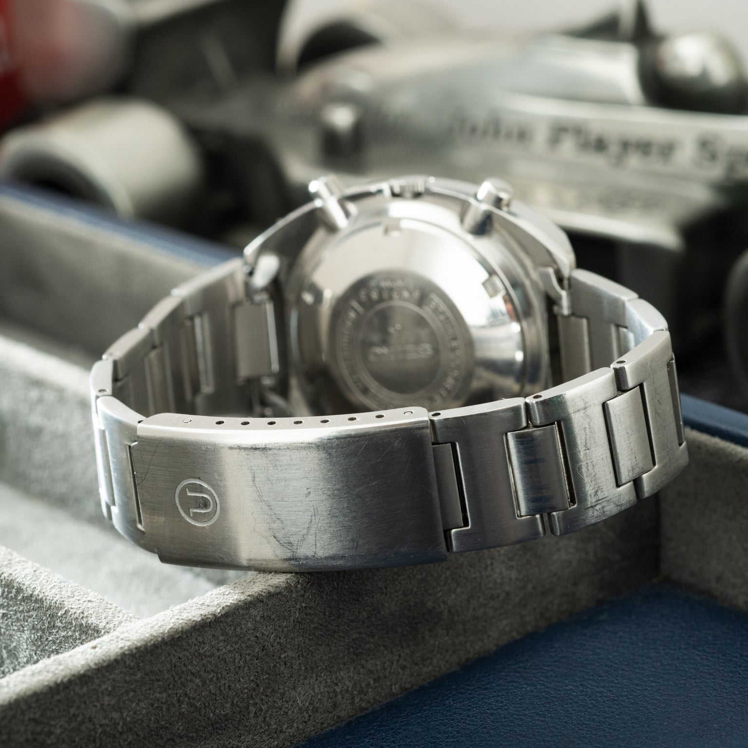Seiko chronograph watch with stainless steel bracelet and dial, displayed on its back showing case back engraving.