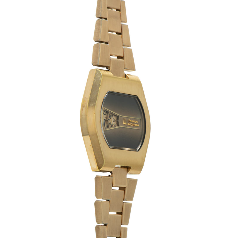Gold-tone Bulova Accutron watch with curved rectangular black digital display and linked metal bracelet.