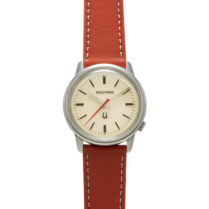 Bulova Accutron watch with cream dial, black hour markers, red seconds hand, and rust-colored leather strap with white stitch