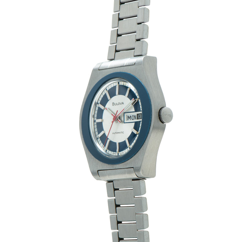 Silver-toned Bulova automatic watch with blue bezel, white dial, day-date window, and metal bracelet.