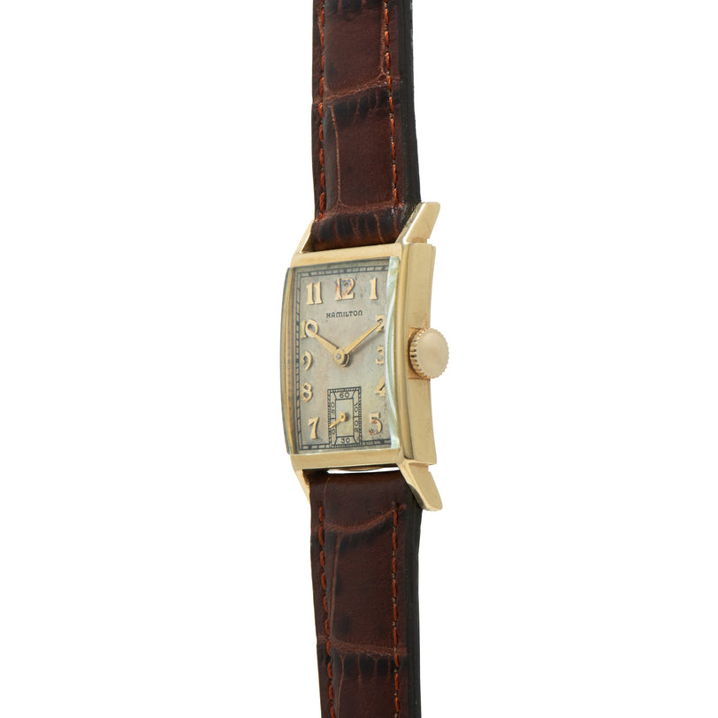Gold-tone rectangular Hamilton watch with cream dial, Arabic numerals, subsidiary dial, and brown leather strap.
