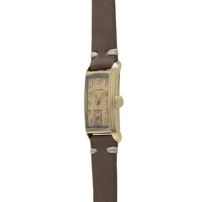 Hamilton Sherwood watch with rectangular gold-tone case, cream dial with Arabic numerals, and brown leather strap.