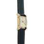 Longines Tank watch with rectangular cream dial, Roman numerals, gold-tone case with hooded lugs, and dark leather strap with