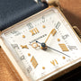 Longines Tank watch with rectangular case, cream dial, gold-tone Roman numerals, and gold hands with blue center seconds hand