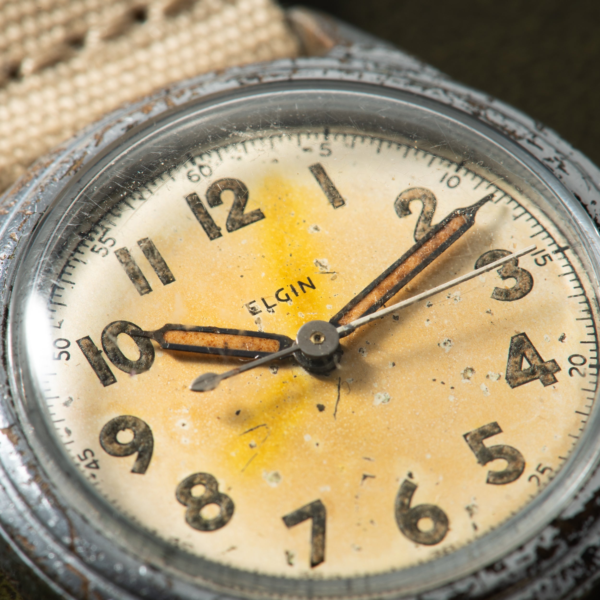 Vintage Elgin watch with cream dial, Arabic numerals, and brown leather strap showing visible patina and wear.