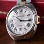 Cartier Clé de Cartier automatic watch with silver case, two-tone bracelet, white dial, and Roman numerals.