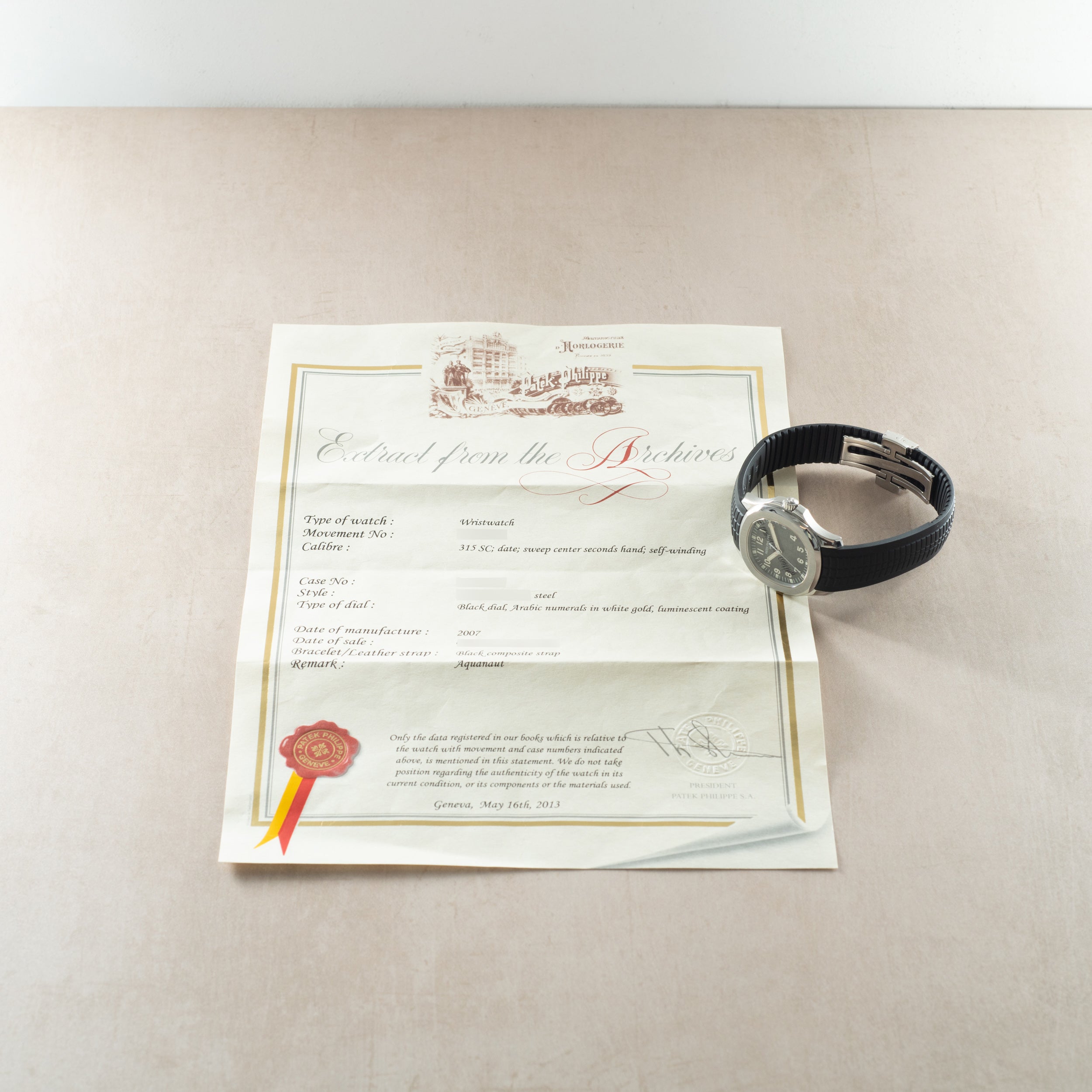 Patek Philippe Aquanaut watch with black rubber strap and silver dial displayed with certificate of authenticity.