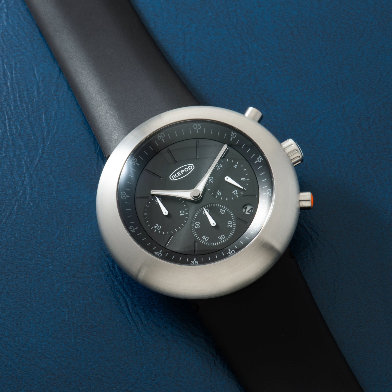 Ikepod Chronopod chronograph with round stainless steel case, black dial, and black rubber strap.