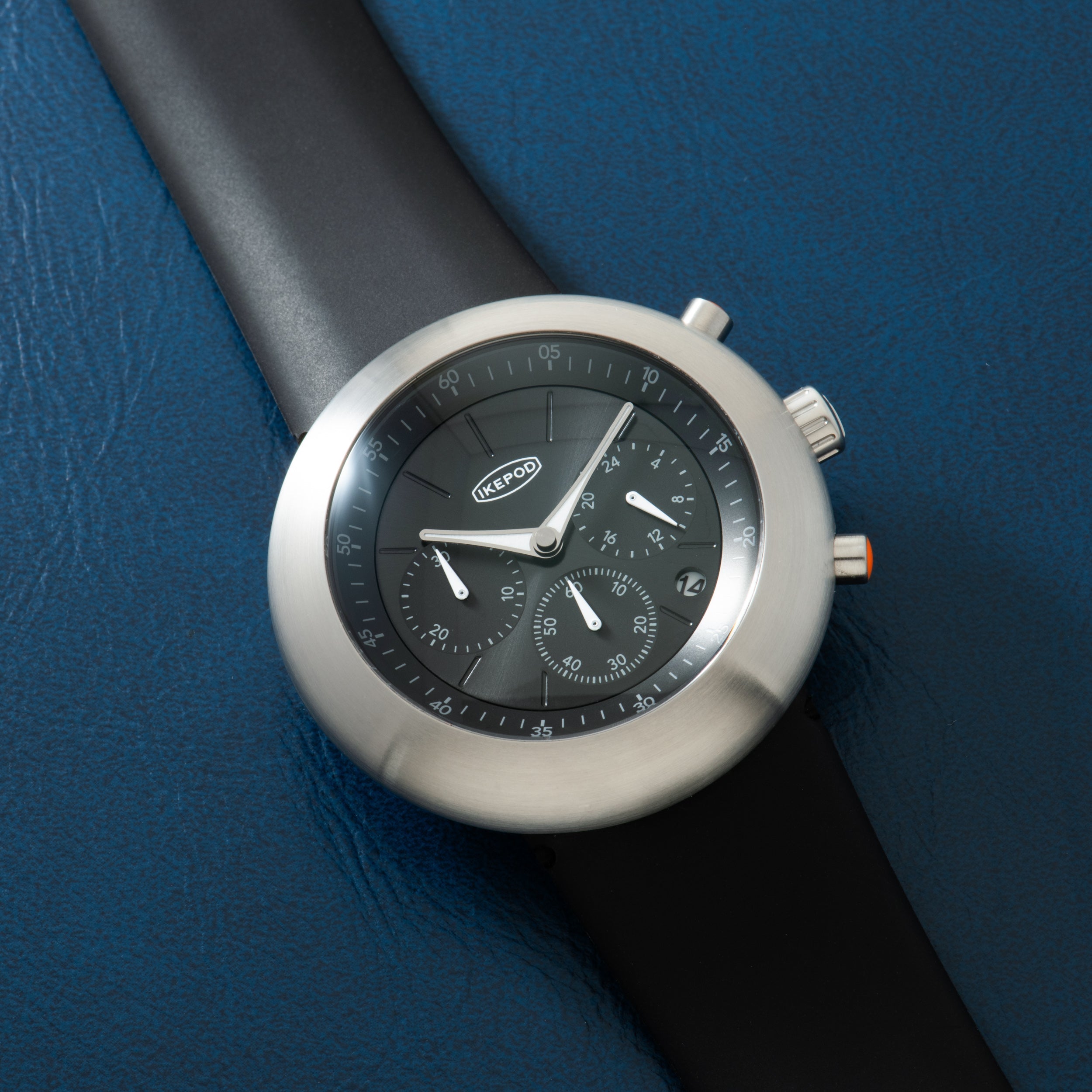 Ikepod Chronopod chronograph with round stainless steel case, black dial, and black rubber strap.