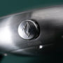 Silver-toned watch crown with leaf engraving on brushed metal watch case.