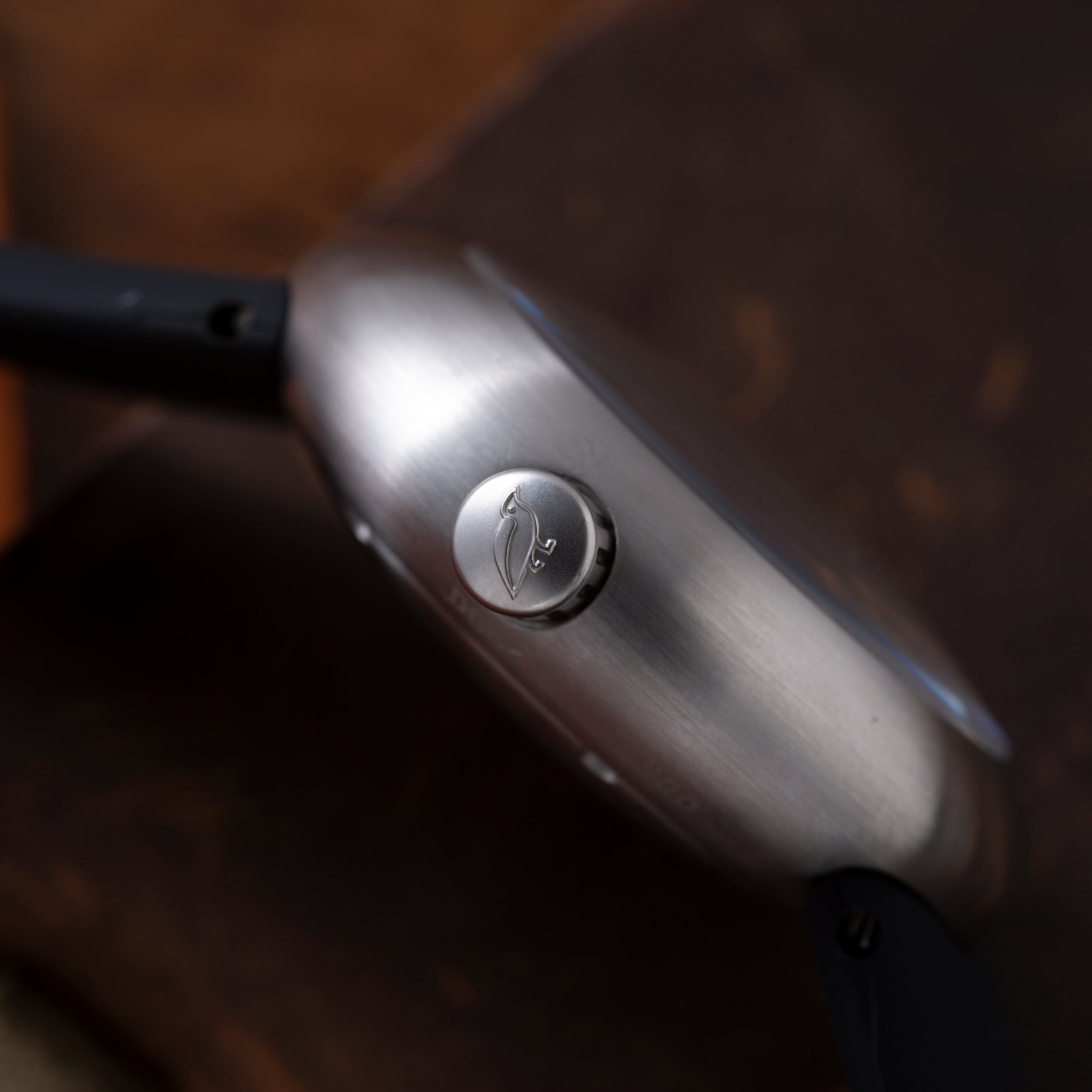 Silver-toned cylindrical watch with brushed metal finish and circular dial featuring minimalist design detail.