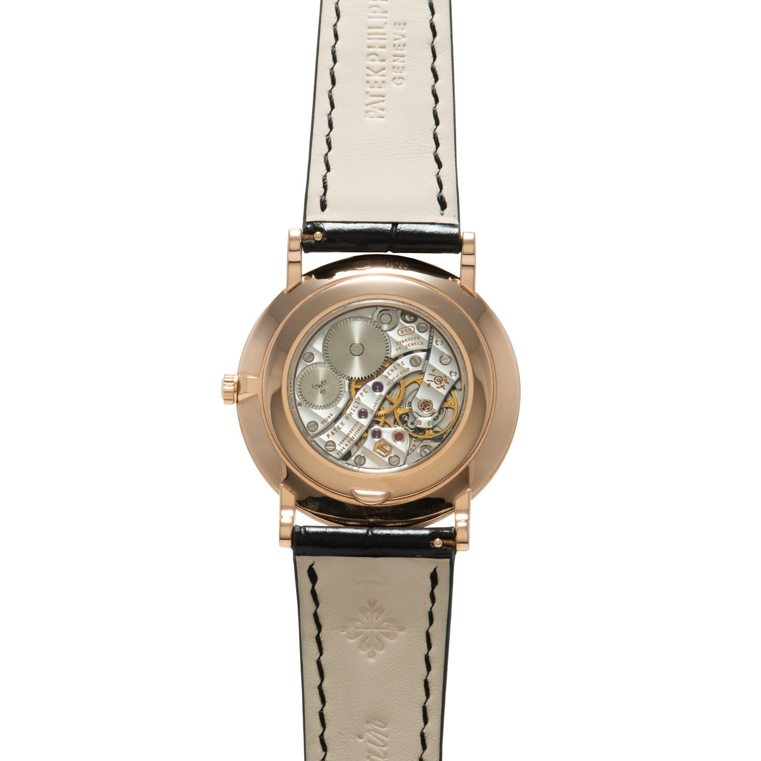 Rose gold watch with skeleton caseback displaying mechanical movement, cream leather strap with black stitching.