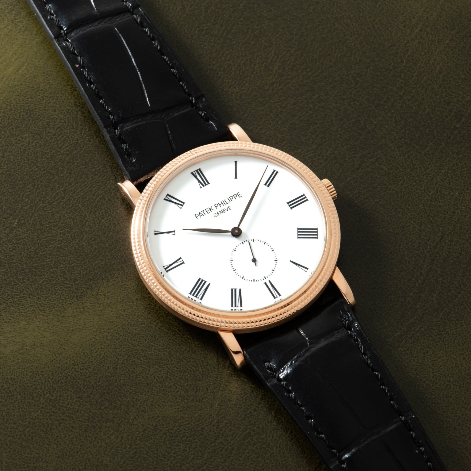 Gold-tone watch with white dial, Roman numerals, small subdial, and black crocodile leather strap.