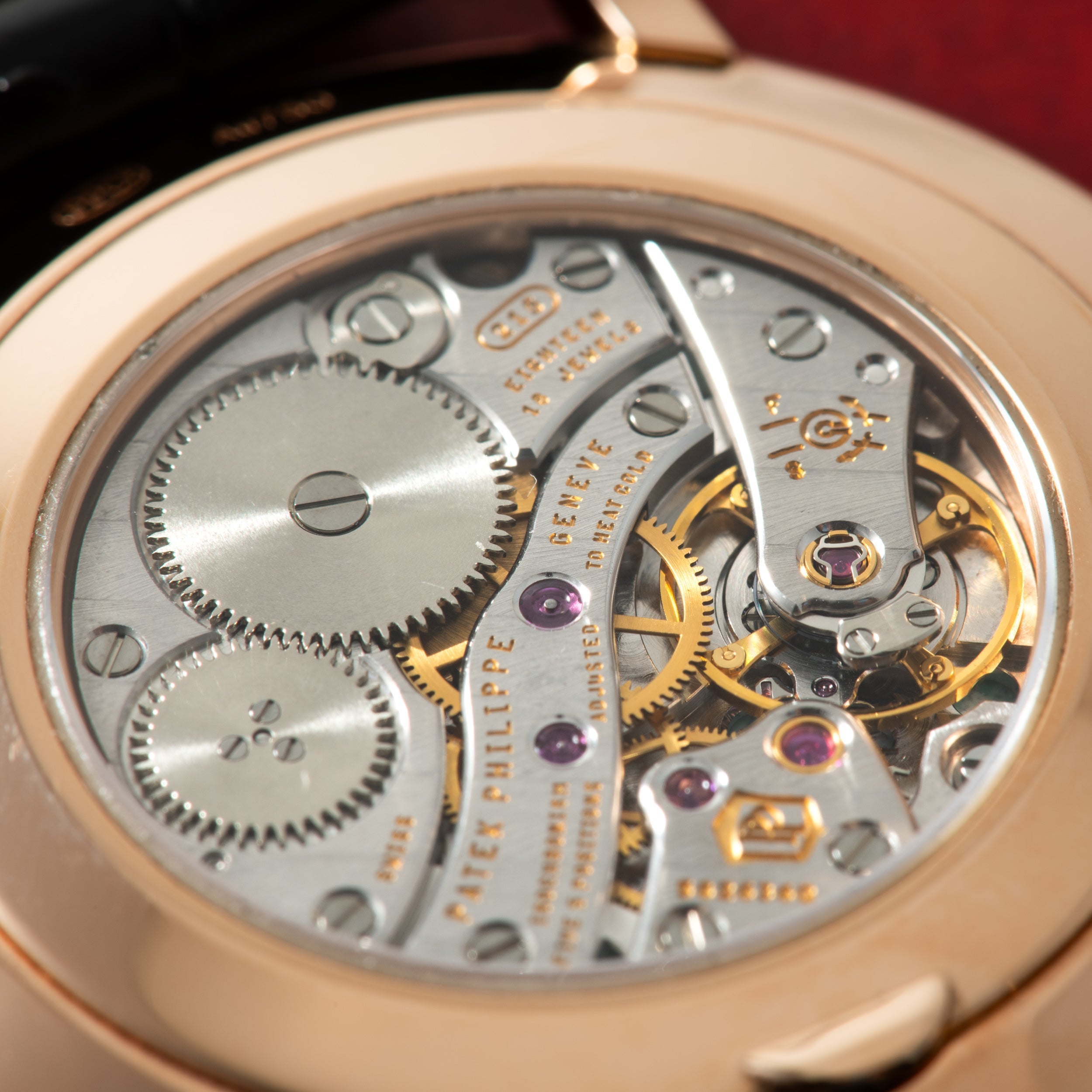 Rose gold watch caseback displaying exposed mechanical movement with gears, jewels, and engraved text.