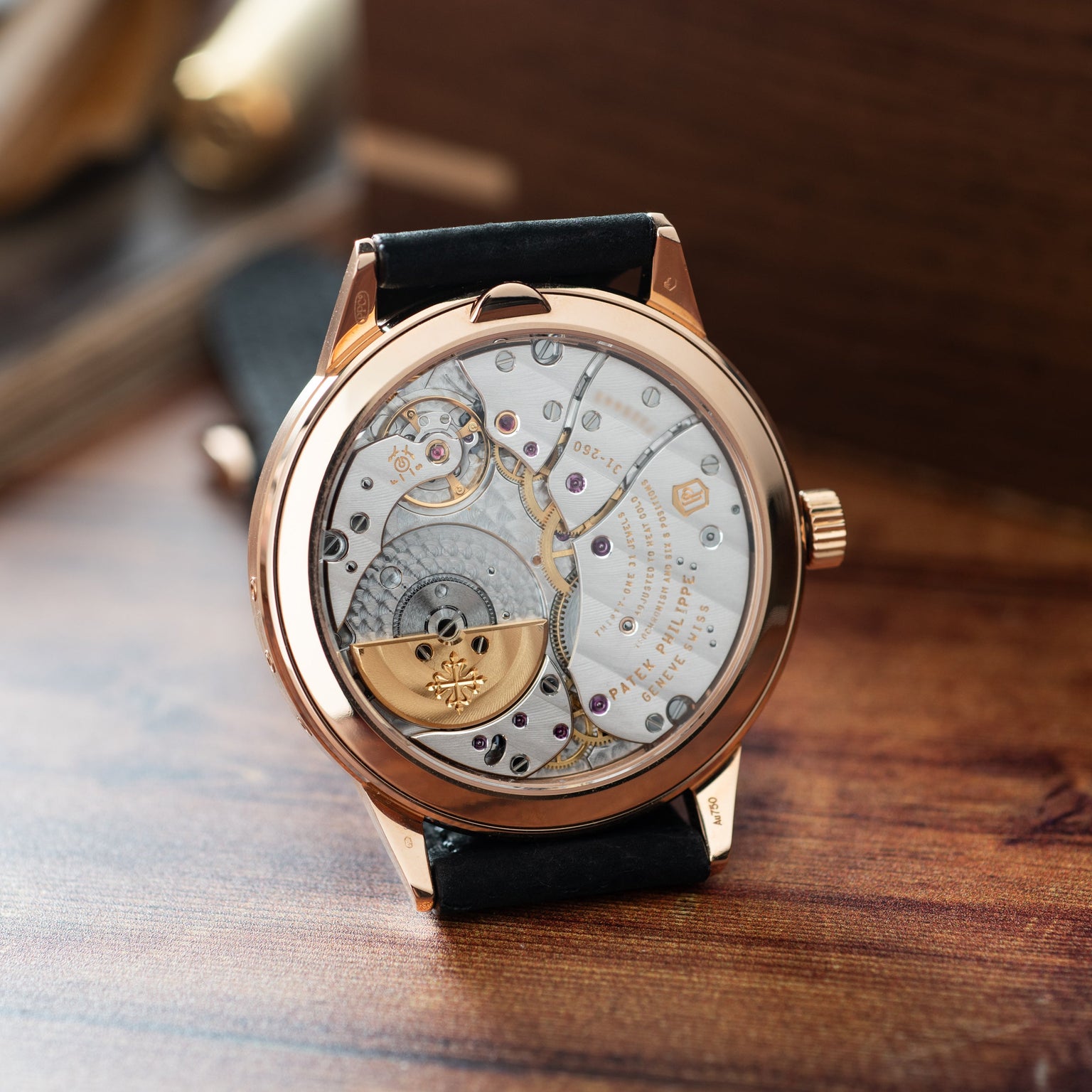 Rose gold watch with skeleton dial displaying visible movement, black leather strap, and regulator-style hour markers.
