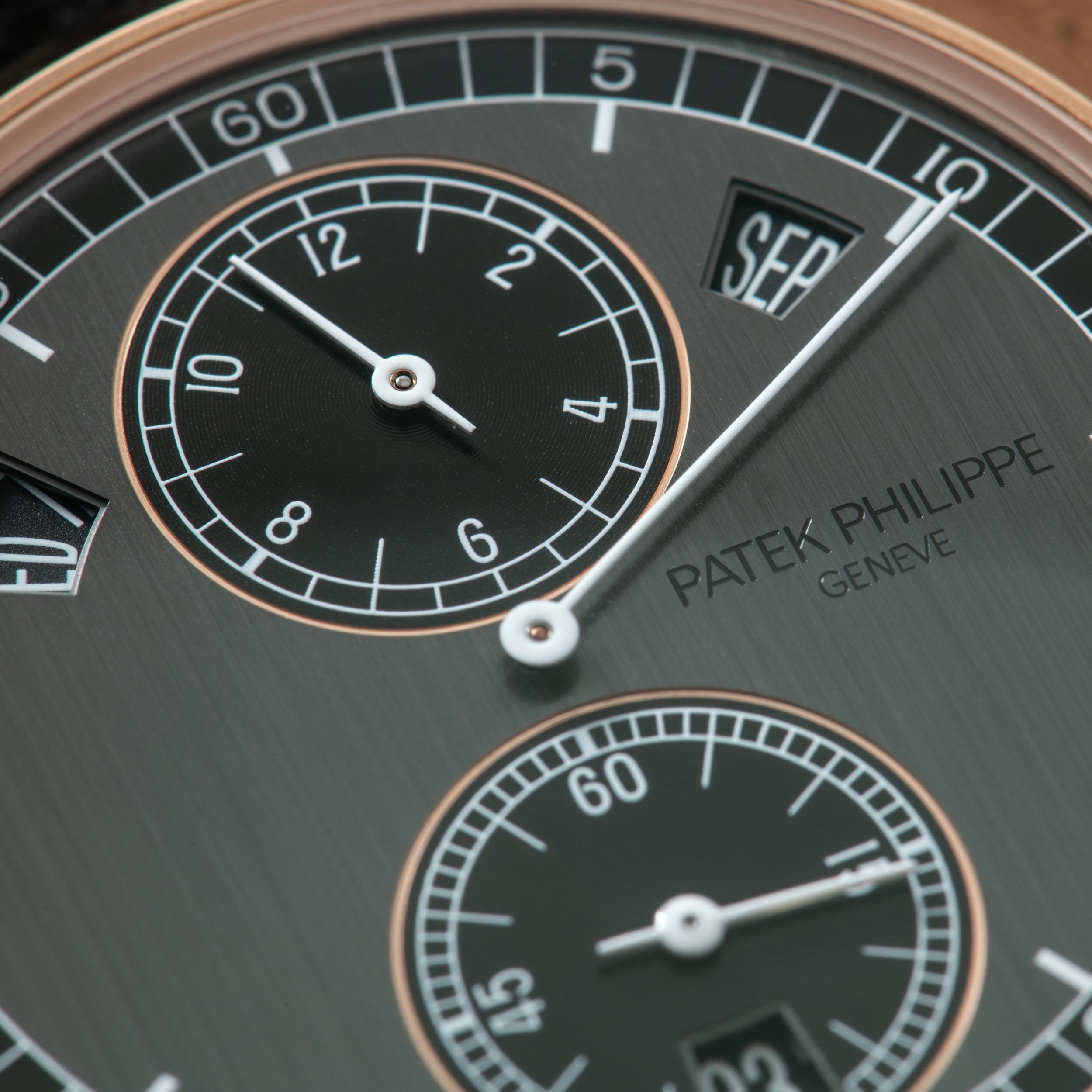 Slate gray watch dial with regulator layout, center hour hand at 3, subsidiary dials with rose gold bezels, "SEP" date window