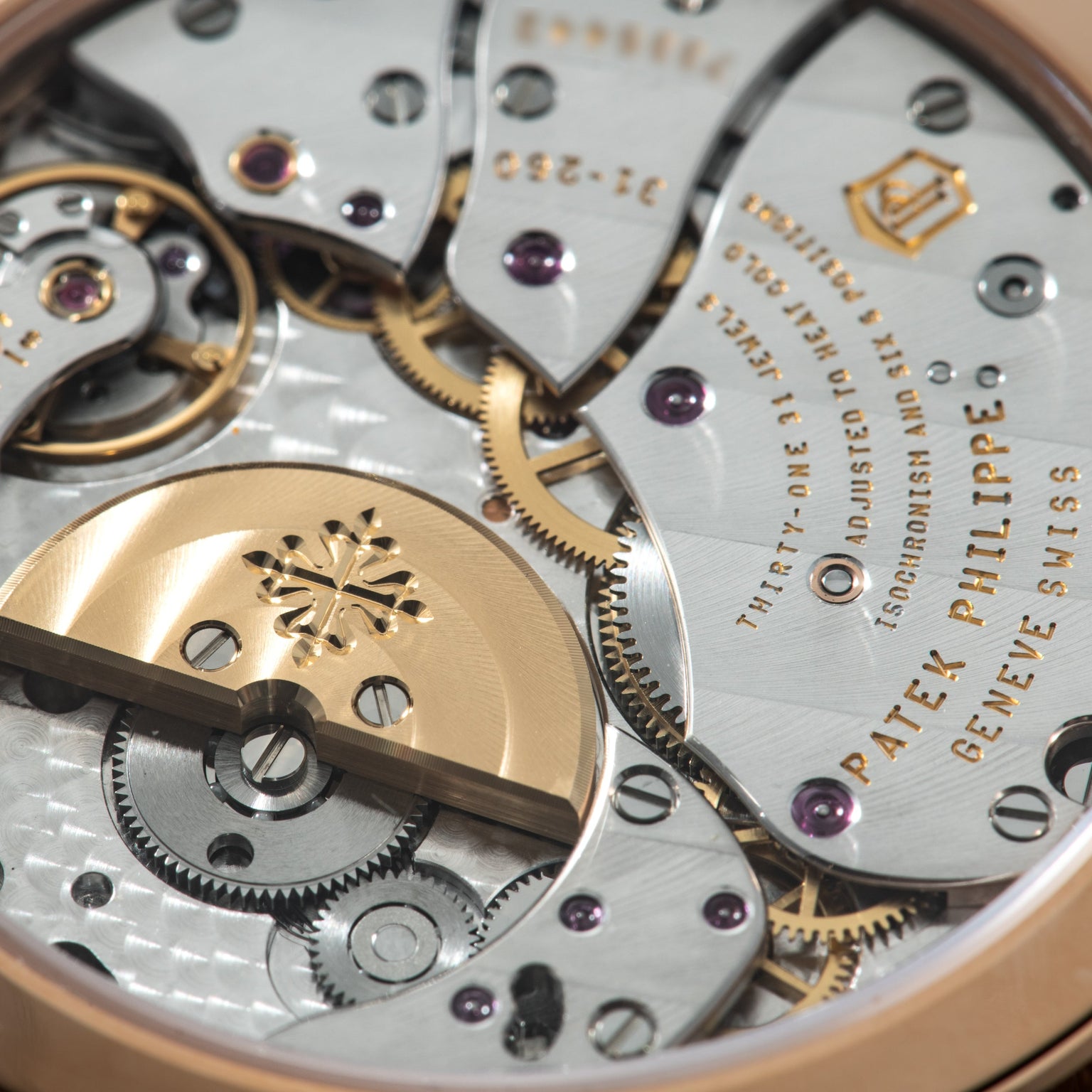Patek Philippe movement with gold and silver gears, jewels, and engraved bridges showing regulator complications.