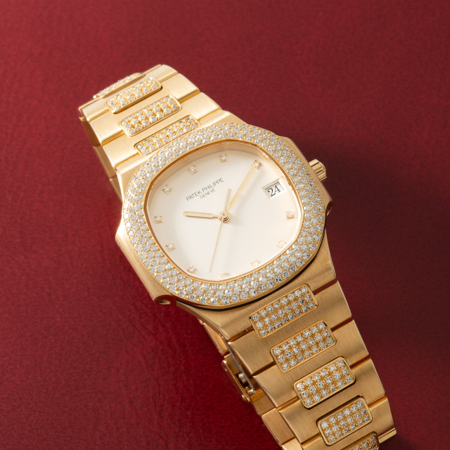 Gold watch with diamond-set bezel, case, and bracelet; white dial with diamond hour markers and date window.
