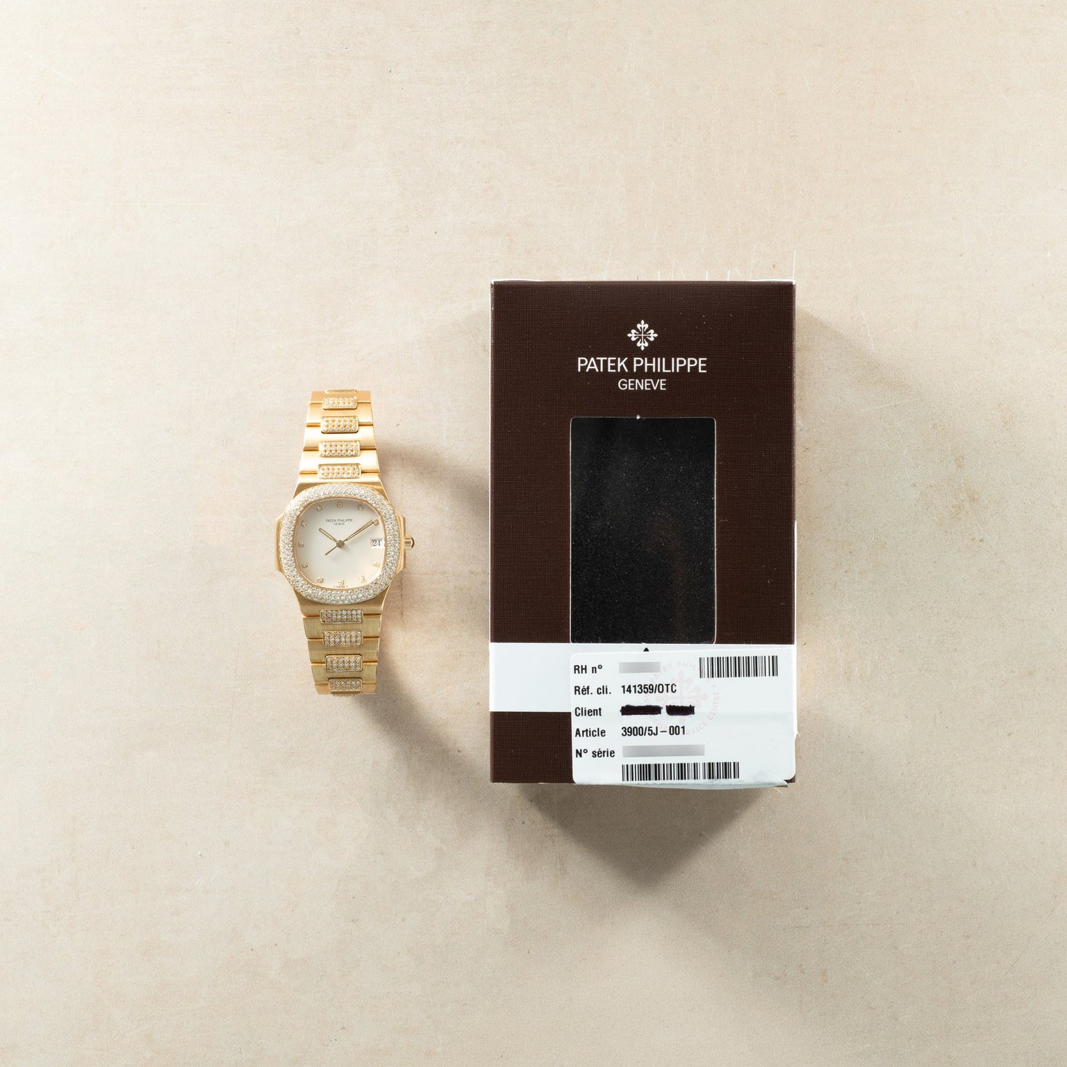 Gold-tone Patek Philippe Nautilus ladies watch with diamond-set bezel and bracelet, displayed next to brown Patek Philippe bo